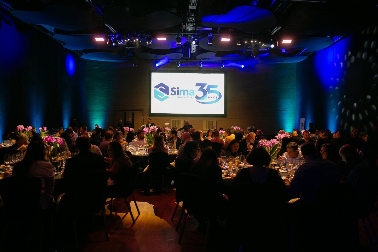Salón de comidas del 35 aniversario de Sima, con el logo en pantalla
